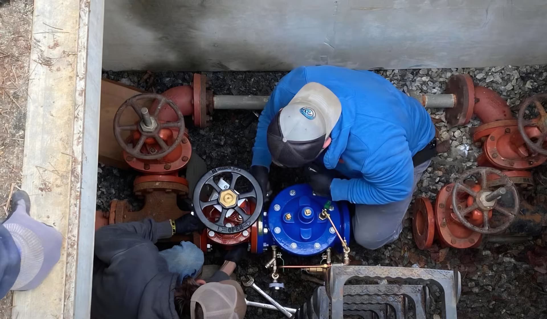 EMS technicians installing a blue valve assembly inside a concrete water vault