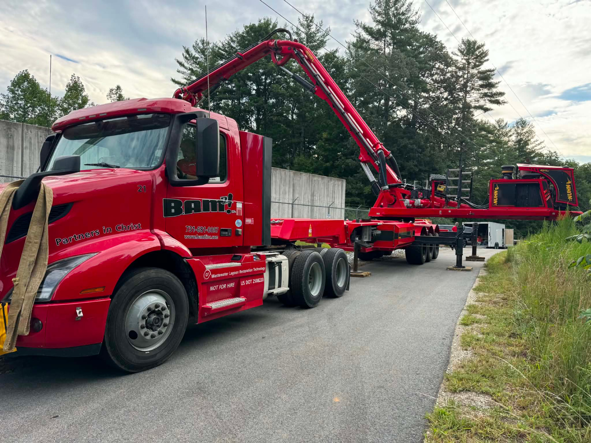 Red concrete pump truck with its boom extended at a construction site