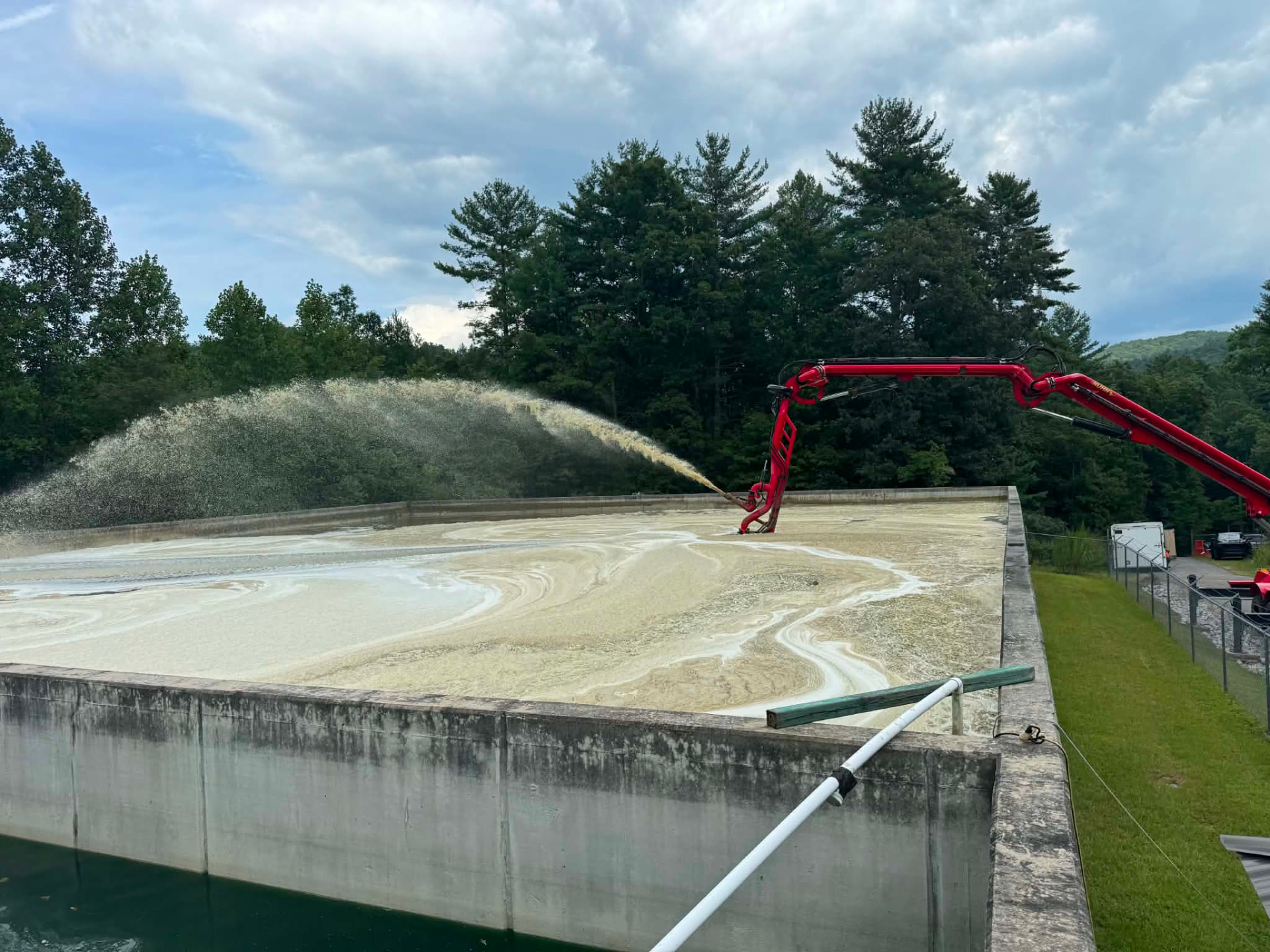 Sludge-removal pump boat spraying across a treatment lagoon operated by EMS
