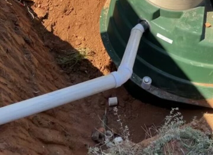 New piping joined to a set Orenco tank at the bottom of a trench