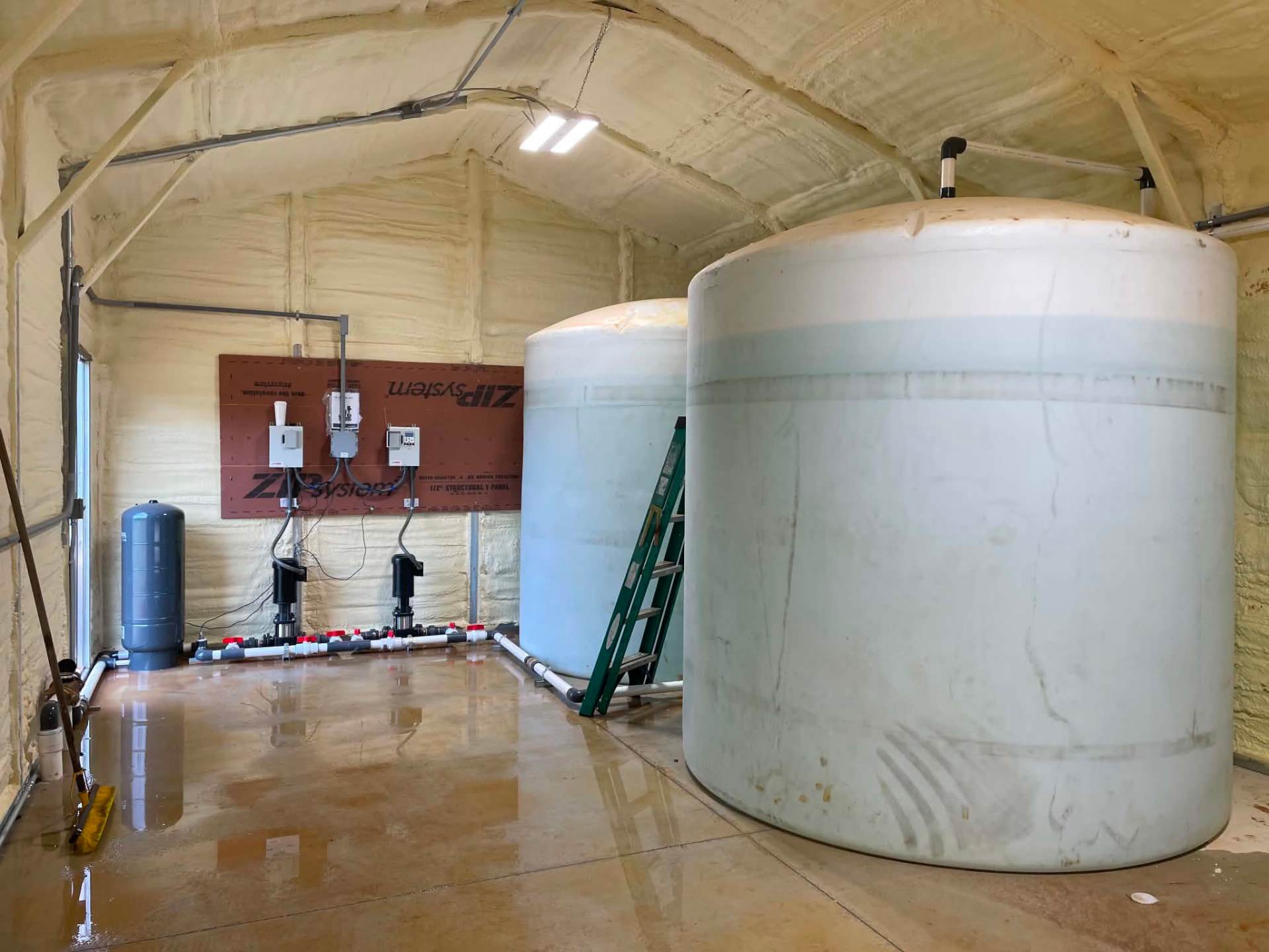 Large treatment tanks and pump controls inside an EMS-operated tank barn.