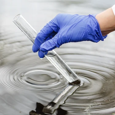 Laboratory technician collecting a water sample for wastewater analysis.